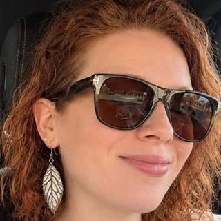 Michelle Feliciano smiling, wearing sunglasses and a leaf-shaped earring